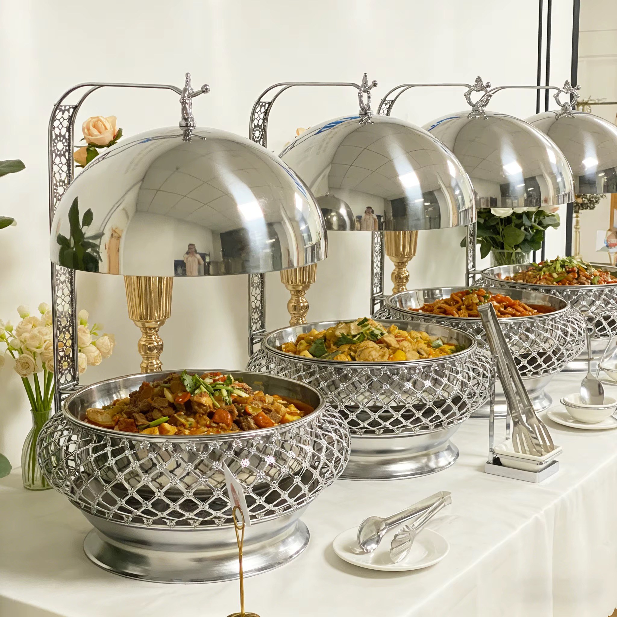 Silver and gold domed buffet serving dishes on a styled event table